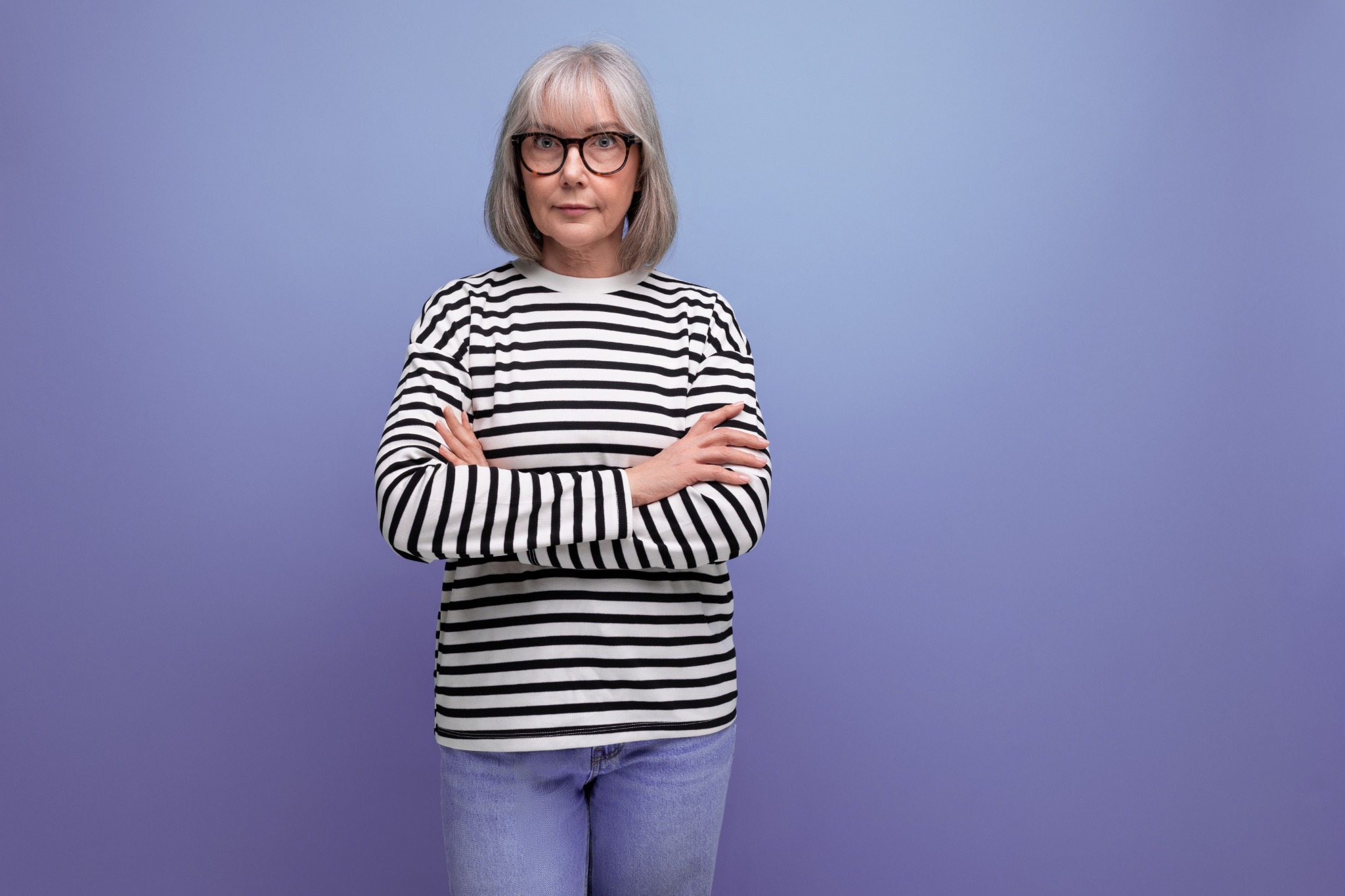 A woman with grey hair and glasses wearing a striped jumper